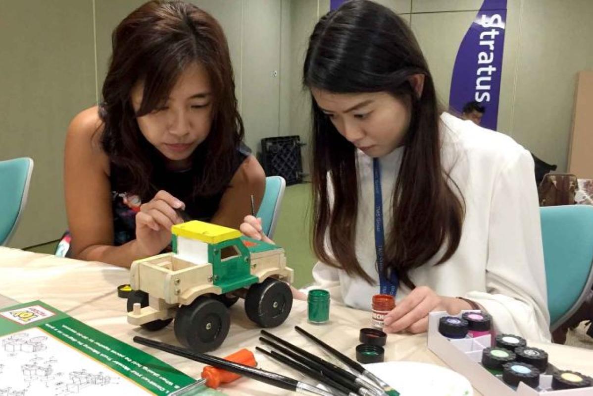 Top 12 Best Team Building Companies In Malaysia 2025 9 Two participants painting a toy trucks as part of the teambuilding activity